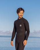 海辺で静かに立つ黒いウェットスーツを着た男性
