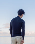 背中を向けた男性が海を見つめている